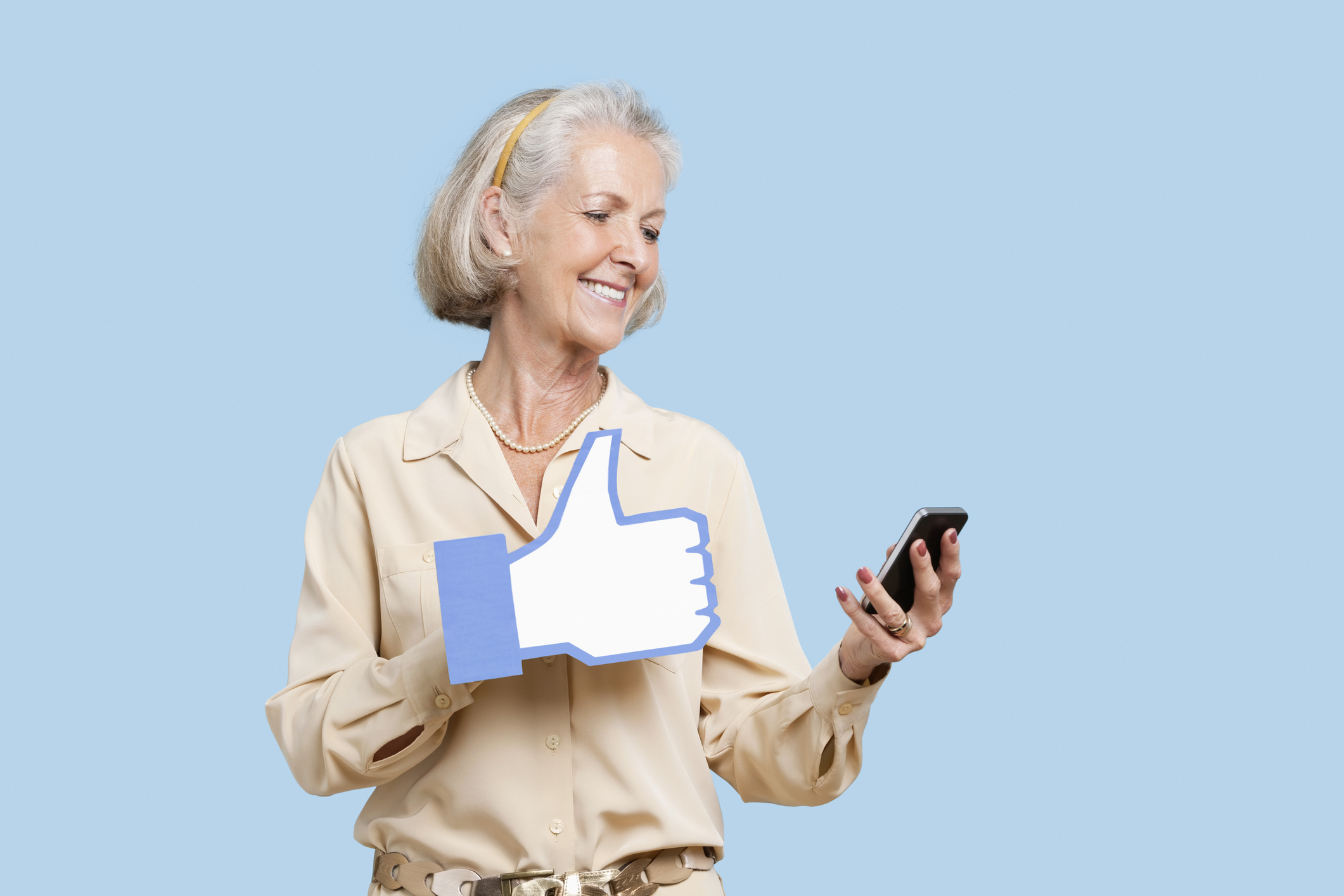 Mature woman giving a thumbs up on smart phone.