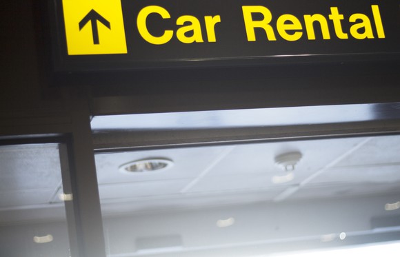 A sign that says Car Rental in yellow letters, with a black arrow to its left.