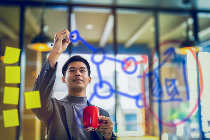 A man writing out strategy on a white board.