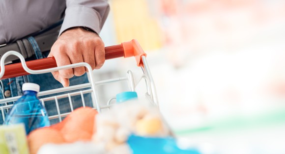 A person in a store with a full grocery cart.