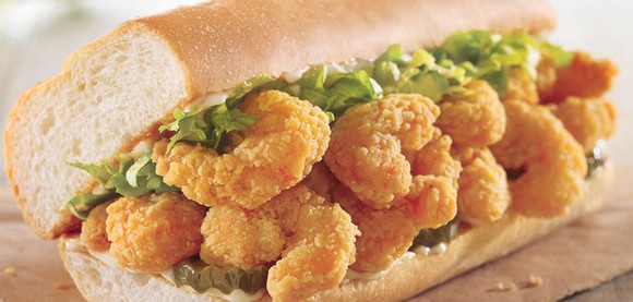 Close-up of fried shrimp and lettuce stuffed into french bread roll.