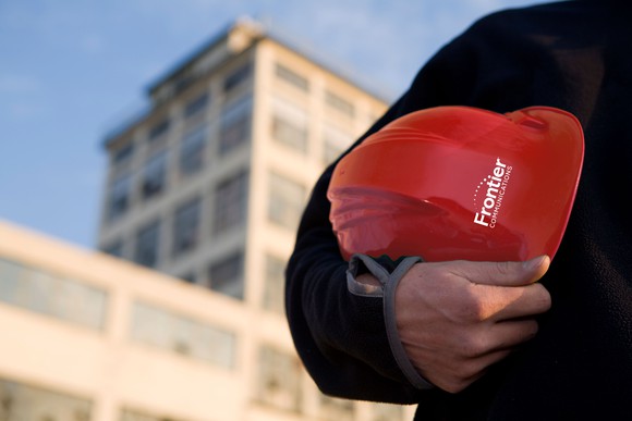 A Frontier worker holding a Frontier hardhat.