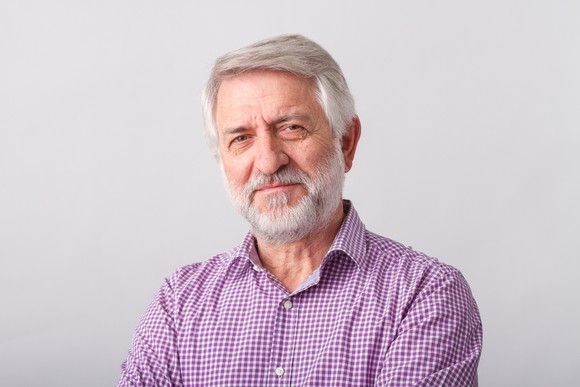 Senior male with gray hair and beard looking serious