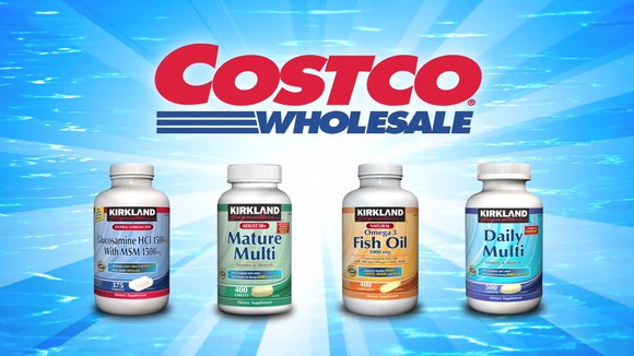 Four bottles of Kirkland vitamins on a bright blue background with Costco Wholesale logo above them.