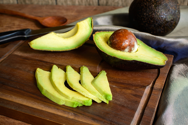 Ripe sliced avocado on wooden chopping board.