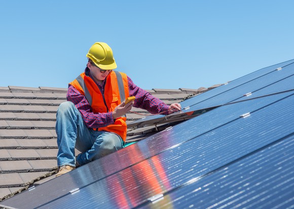 Worker inspecting a rooftop solar installation.