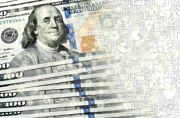 A small fanned stack of hundred dollar bills being transformed into digital currency.