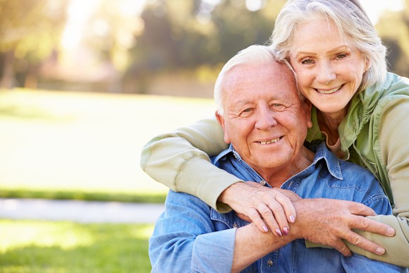 Senior woman with arms around senior man