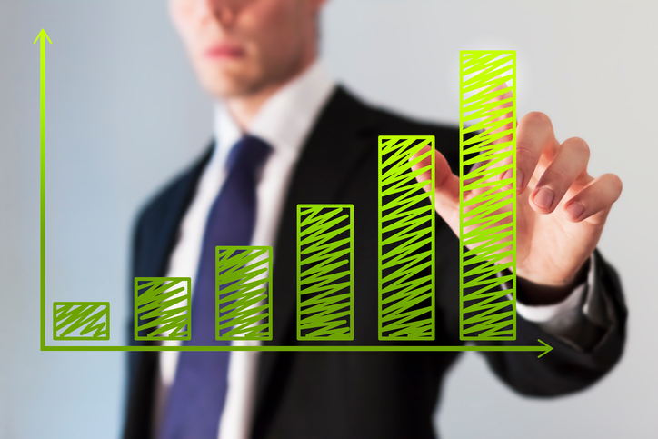 An investor looking at a green bar chart showing growth.