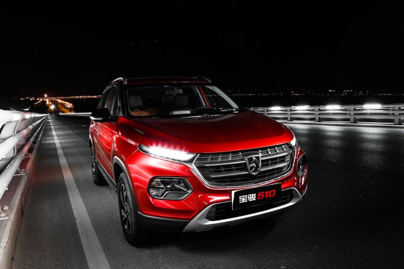 A red Baojun 510 SUV on a bridge, at night.