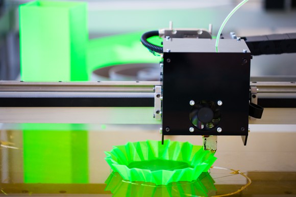 A 3D printer printing an unidentifiable bright green plastic object.