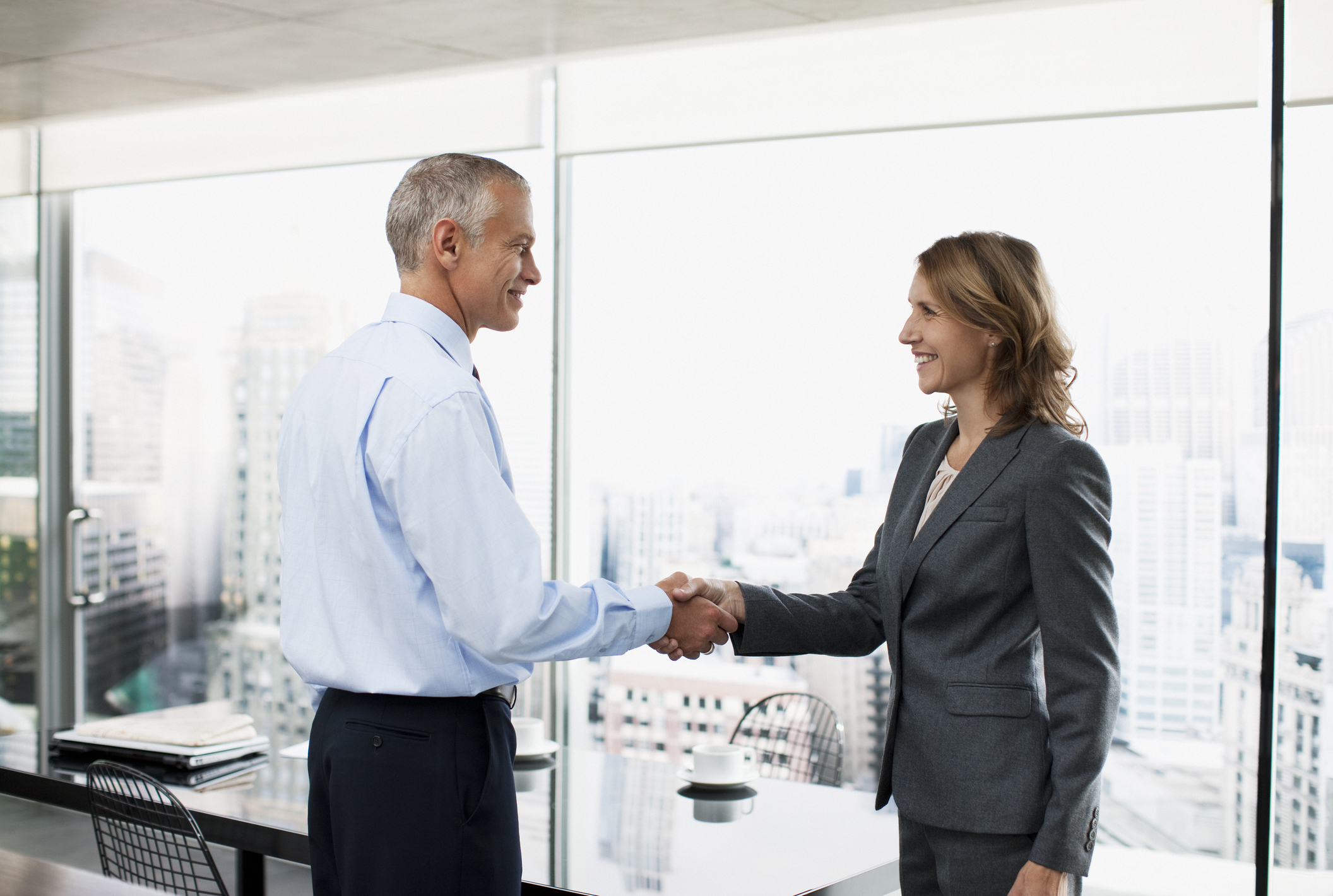 Professional older man shaking hands with a woman in a business suit