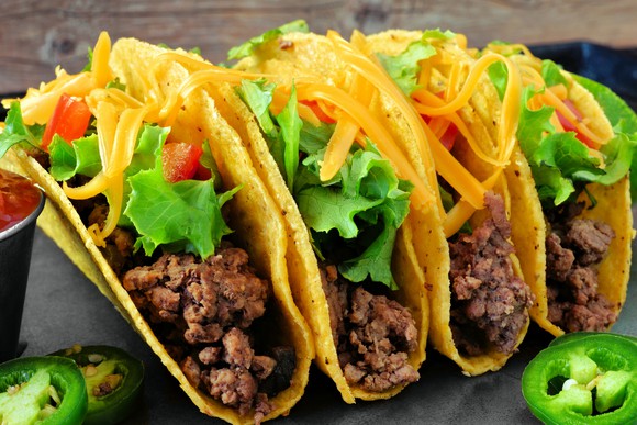Four crispy corn shell tacos with lettuce, cheese, tomatoes, and jalapeno slices