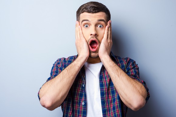 A man clasping his hands to his cheeks with a horrified expression.