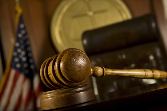 A courtroom, with a judge's gavel, chair, and seal visible.