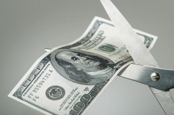 Scissors cutting a $100 bill in half.
