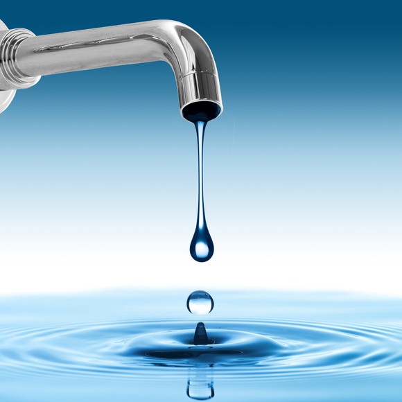 Droplets of water coming out of a faucet and forming a body of water.