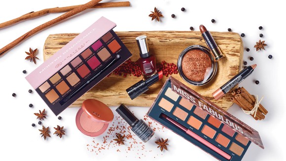 Several different cosmetic products on a white background and wood plank.