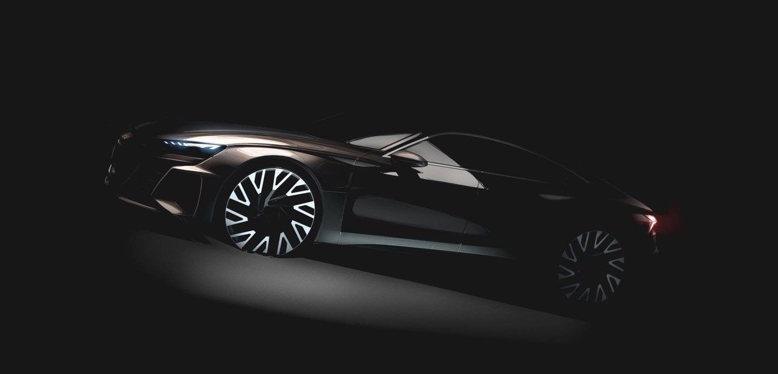The prototype Audi e-tron GT, a low-slung four-door shown in shadows.
