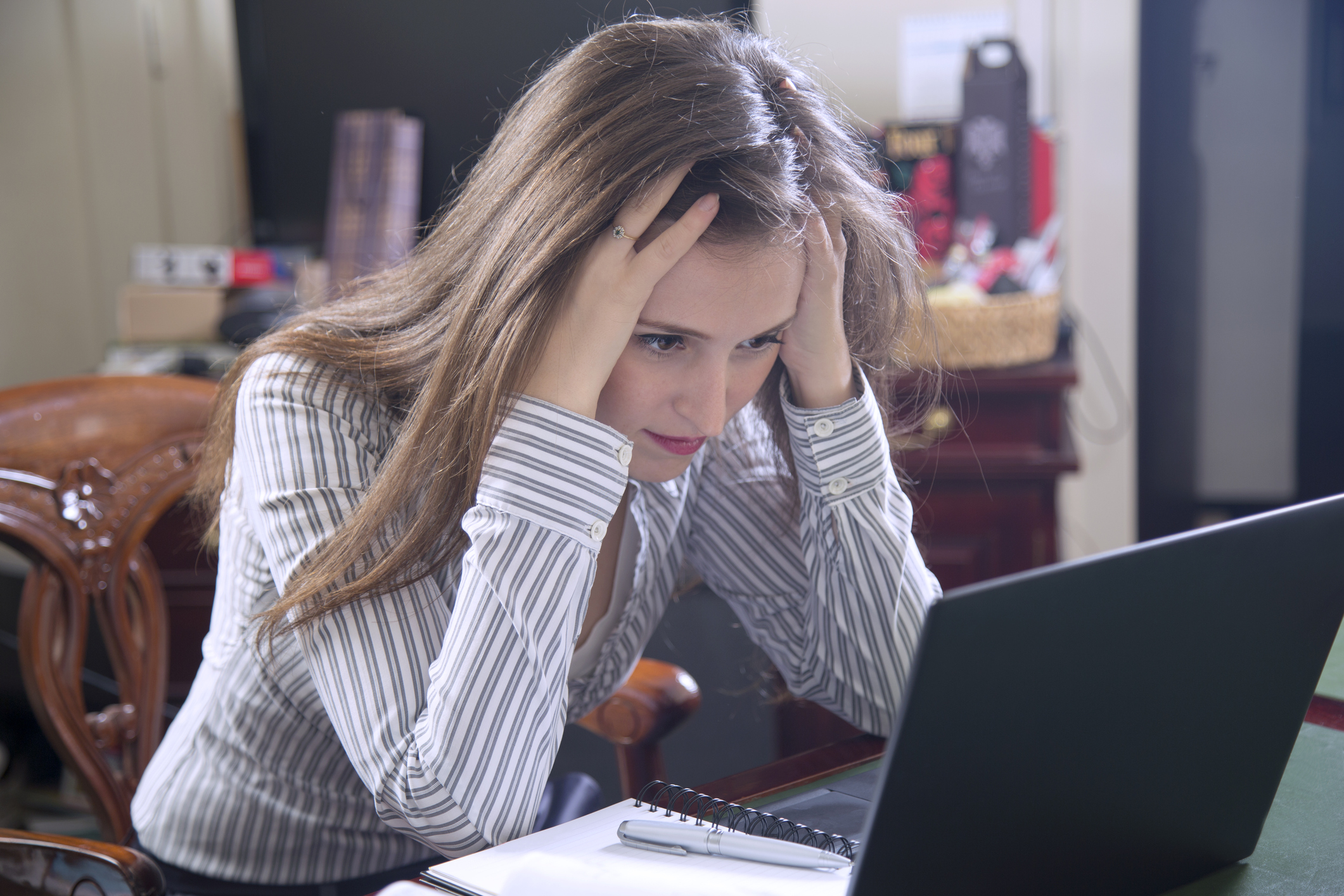 A frustrated woman looking at a laptop.