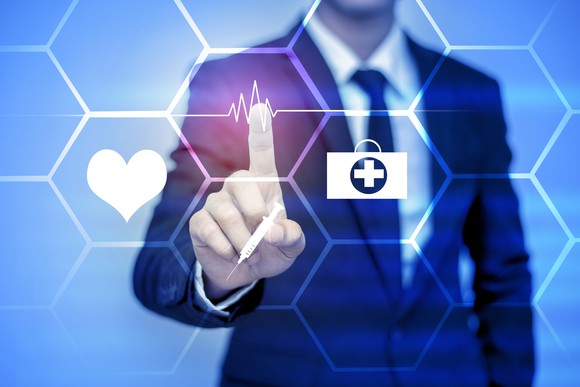 Businessman pointing to healthcare icons on virtual screen