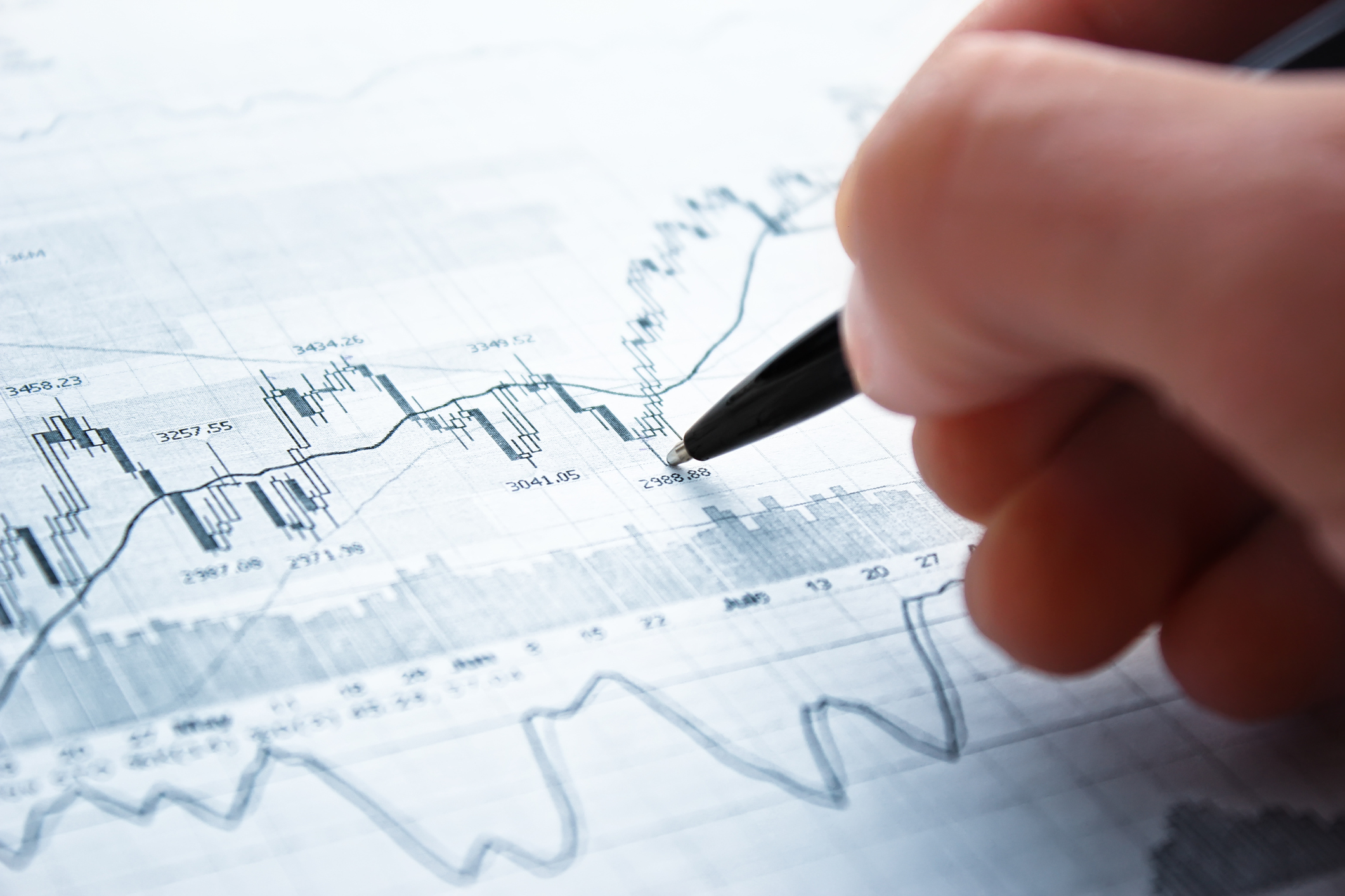 A person using a pen to analyze stock market movements.
