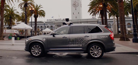 A Volvo SUV with Uber logos and visible self-driving sensor hardware is shown parked in San Francisco.