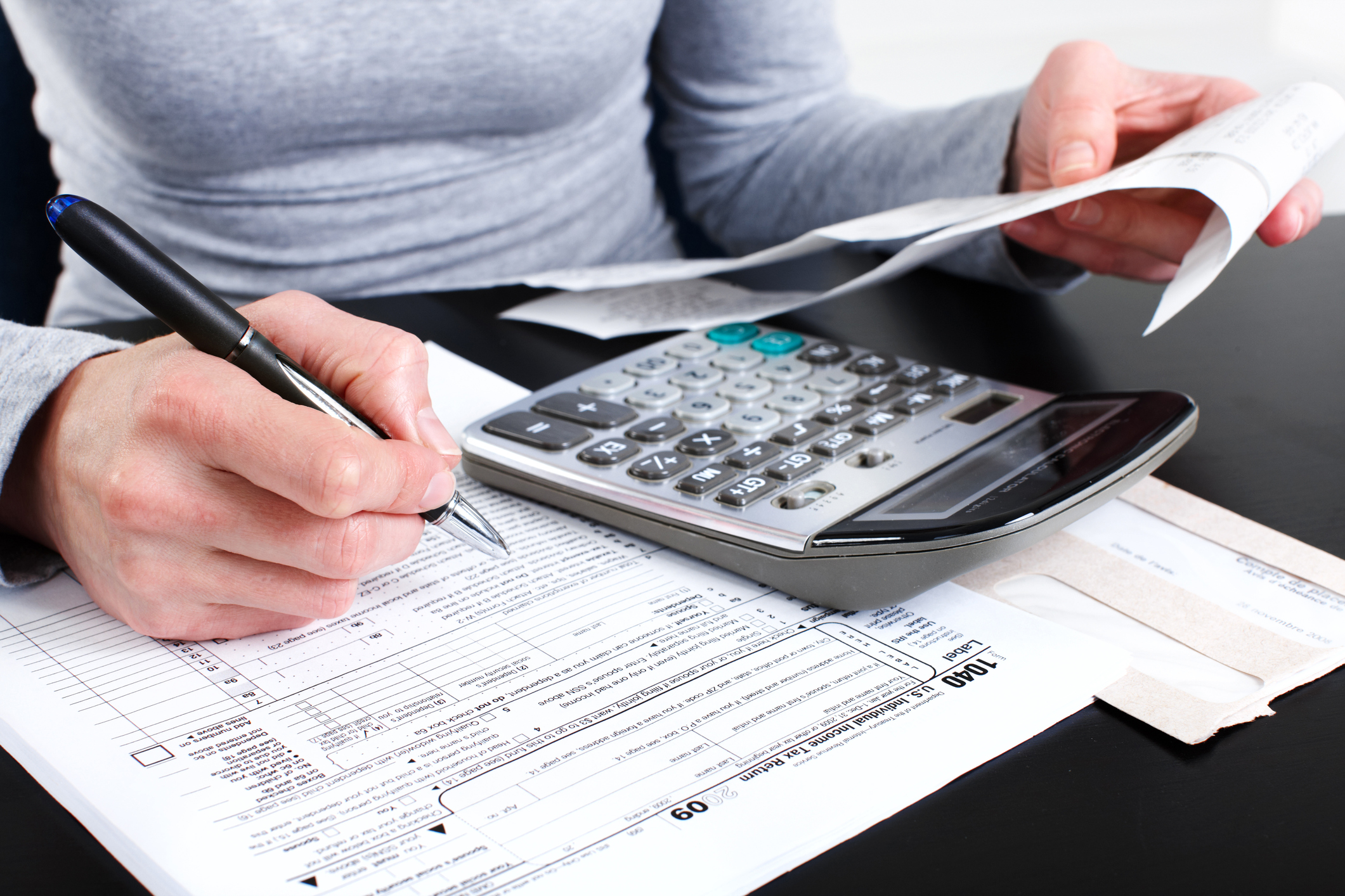 Woman filling in a tax form with a calculator in lap