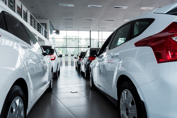 Two lines of cars parked in a dealership showroom.