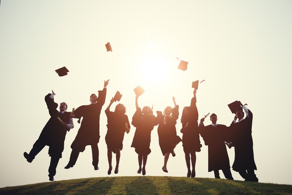 Robed college graduates throw their caps in the air.