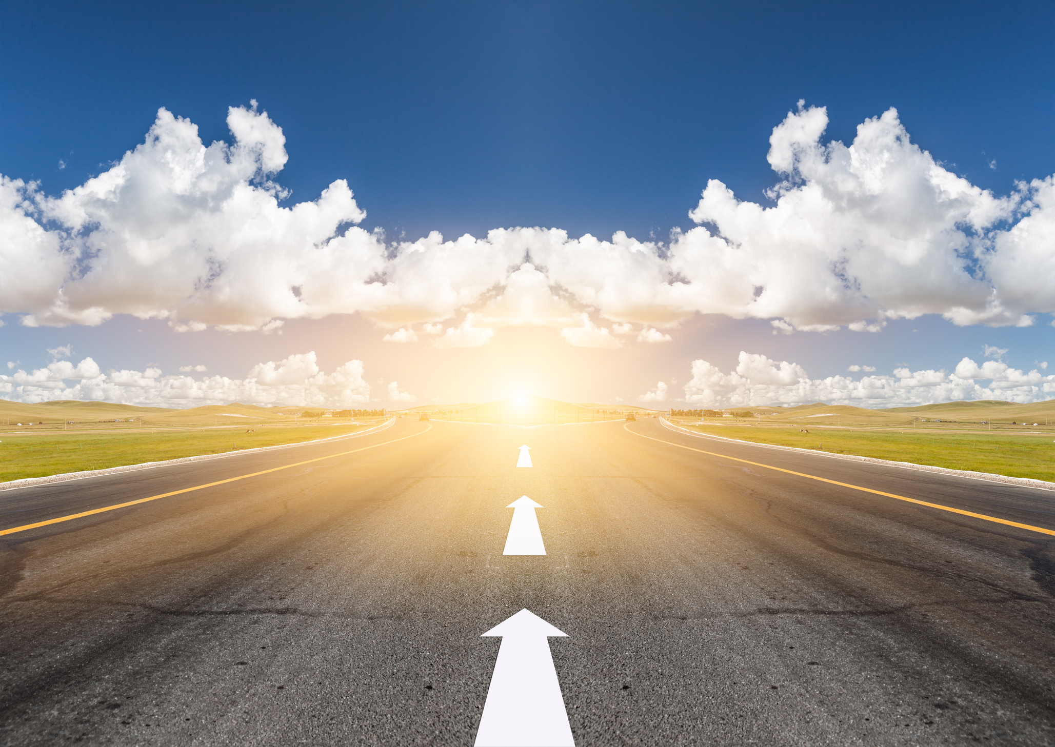 A road with arrows pointing forward towards a bright sun.