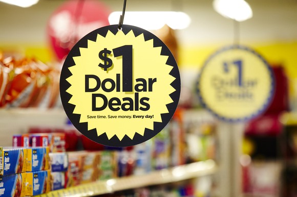 Close-up of hanging sign labeled "$1 Dollar Deals" in Dollar General store aisle.