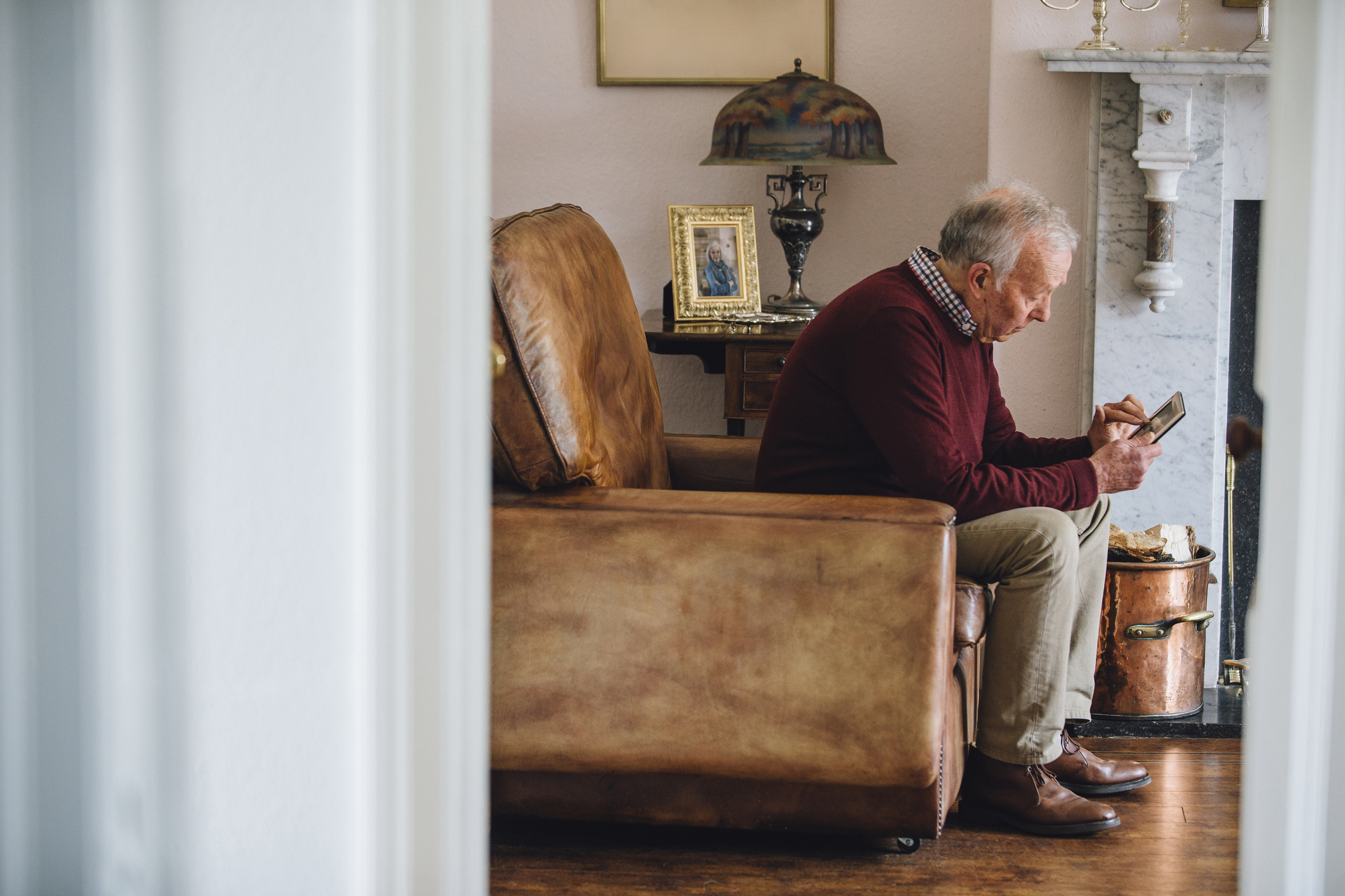 Senior man sitting in an armchair and holding a tablet.
