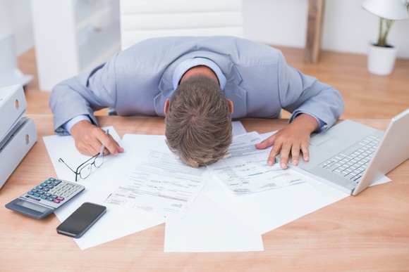 Professional man with his head down on a desk full of papers