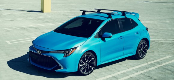 A blue 2019 Toyota Corolla hatchback, a small sporty-looking four-door car, photographed from above in a sunny parking lot.