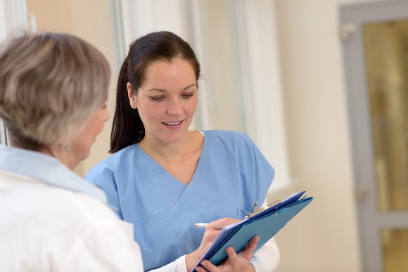 A nurse filling out a patient's chart as a doctor looks on.