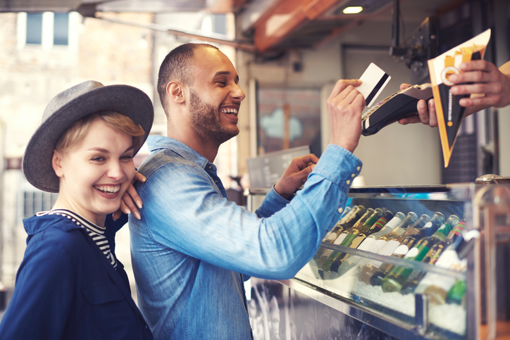 Young man paying for fries with credit card at food kiosk.