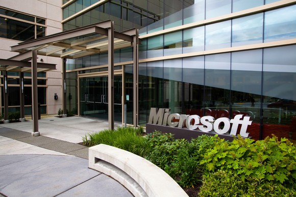 Office building front with Microsoft logo in a garden area next to the entrance.