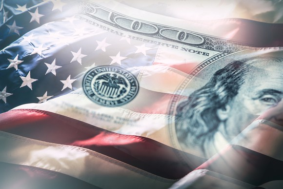 An American flag interposed with a $100 bill.