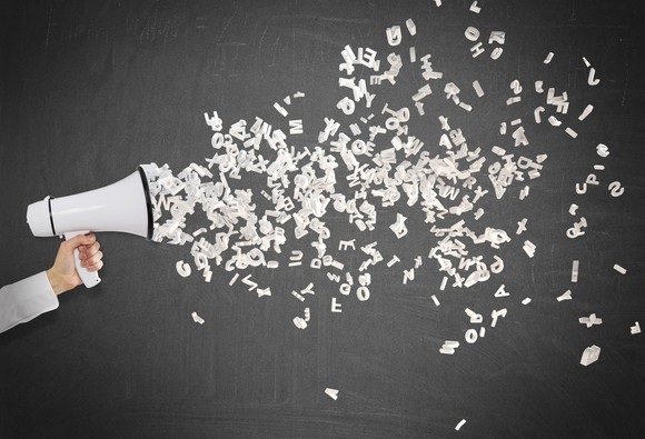 Letters shoot out of a megaphone being held by a hand.
