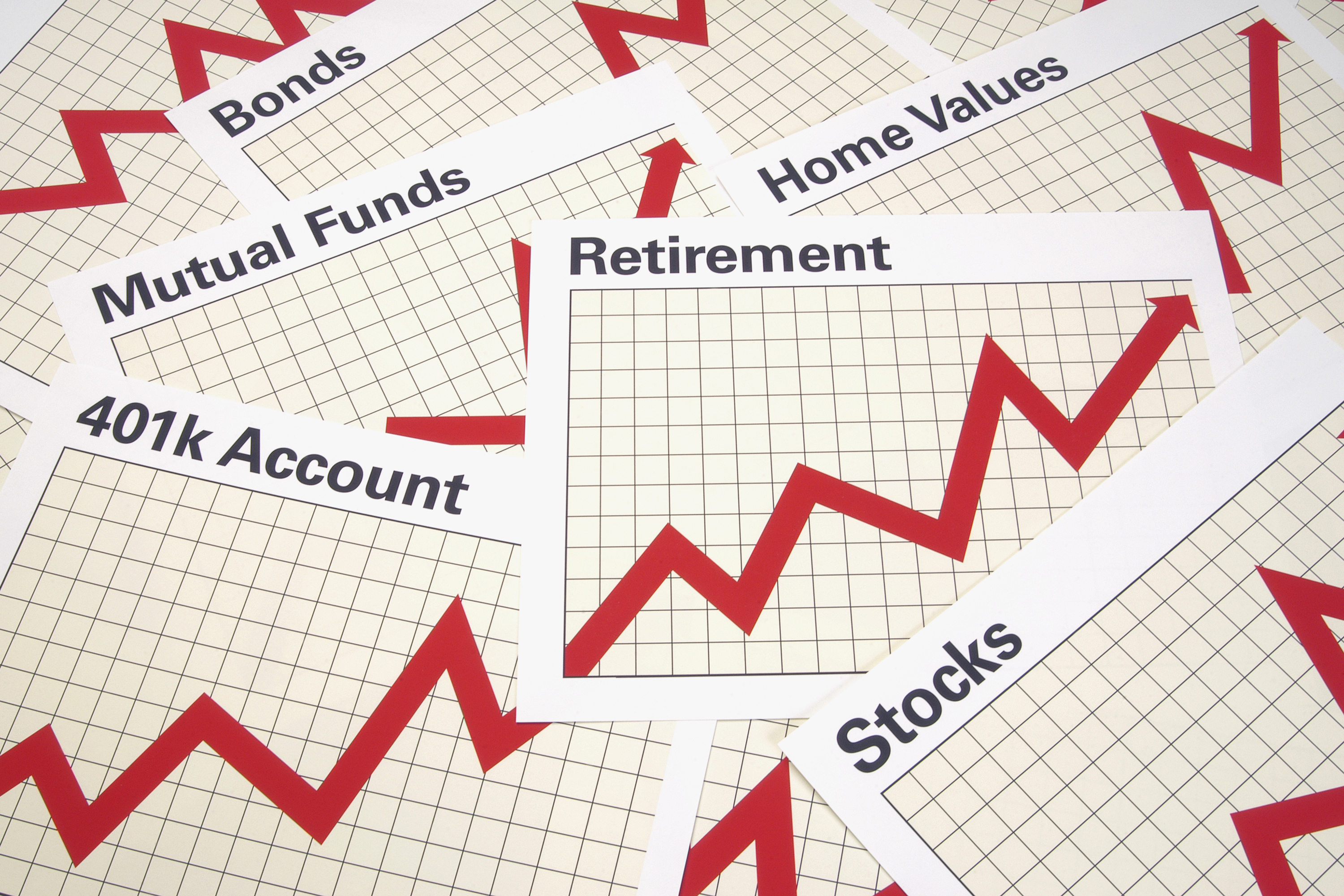 Overlapping pieces of paper, each of which sports a red graph line and words such as stocks bonds mutual funds retirement and so on.