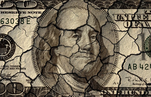 A $100 bill painted on a cracked and crumbling surface.