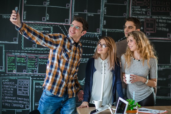 Young adults taking a selfie in front of a blackboard