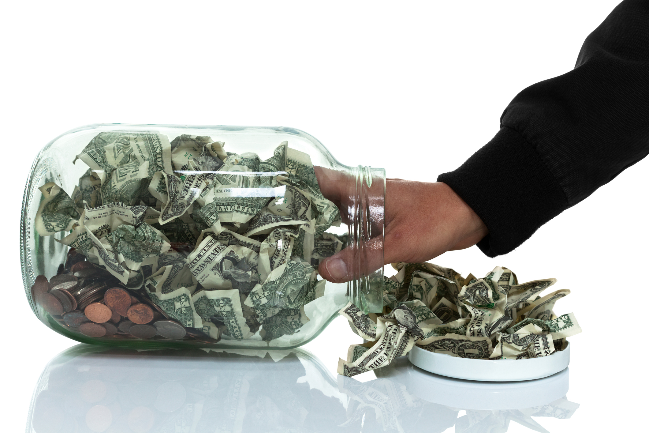 Person's arm taking money from a jar.