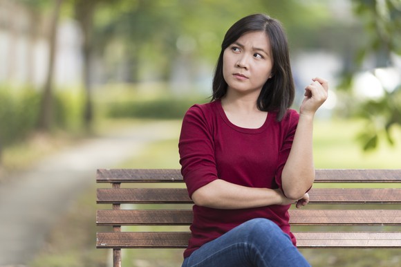 woman sitting on a bench looking confused or questioning