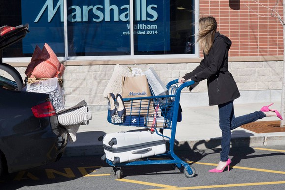 A woman with a shopping cart in front of a Marshalls store