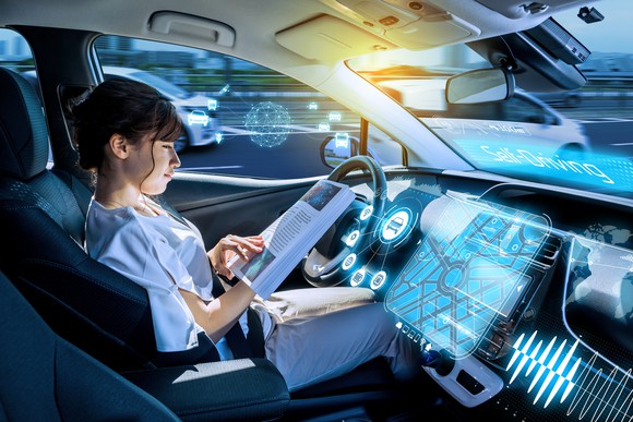 A woman reads a book in a driverless vehicle.