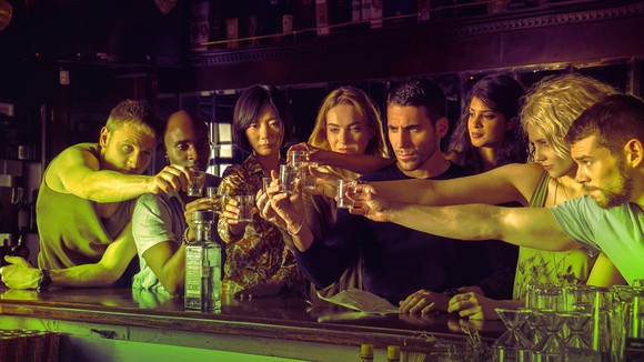 The cast of Sense 8 raise a toast at a bar.