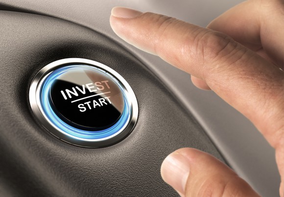 A finger about to press a button labeled invest/start.