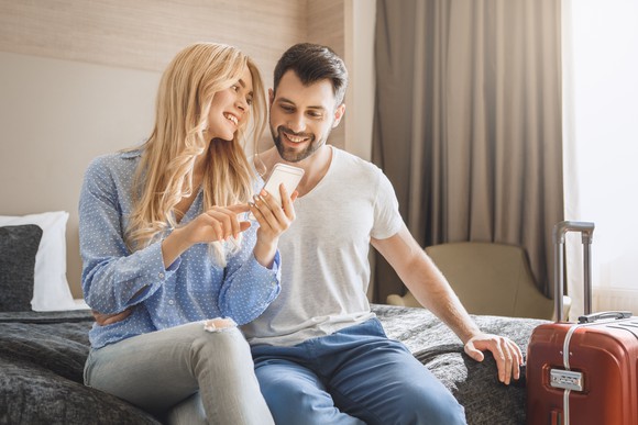 A couple browsing a smartphone in a hotel room.